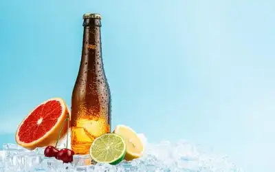 Garrafa de cerveja gelada sem rótulo sobre gelo, com grapefruit, cerejas, limão e lima