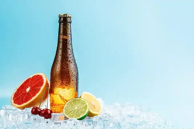 Garrafa de cerveja gelada sem rótulo sobre gelo, com grapefruit, cerejas, limão e lima