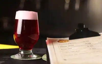 Taça tulipa com cerveja vermelha e cardápio de chopp artesanal sobre balcão