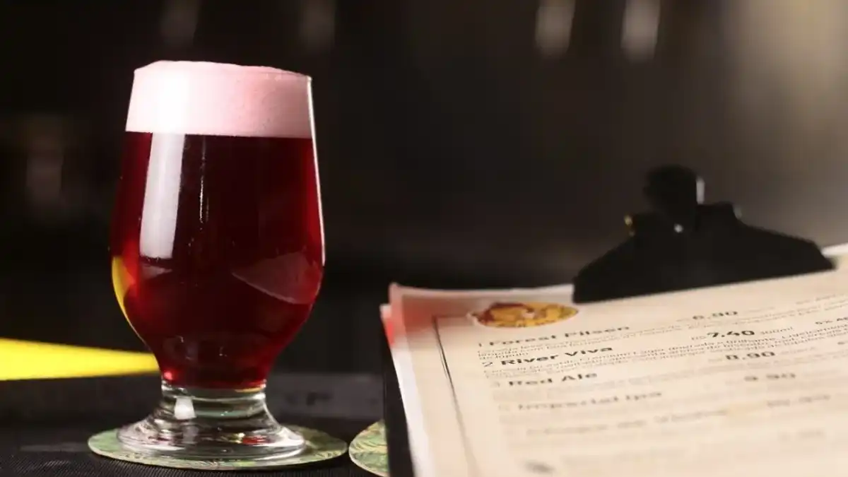 Taça tulipa com cerveja vermelha e cardápio de chopp artesanal sobre balcão