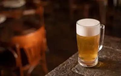 Copo de cerveja Pilsen dourada e brilhante com colarinho de espuma branca