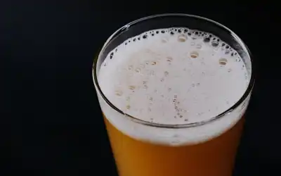 Copo alto de cerveja Weiss turva e dourada com espuma branca cremosa